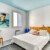 Chambre lumineuse décorée dans un esprit marin, avec tableaux et mobilier coloré.