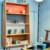 Détail d’un coin lecture décoré dans un style scandinave avec étagère en bois clair.