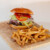 Burger gourmet avec frites maison sur planche en bois