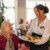 Serveuse souriante servant un repas à une résidente en maison de retraite